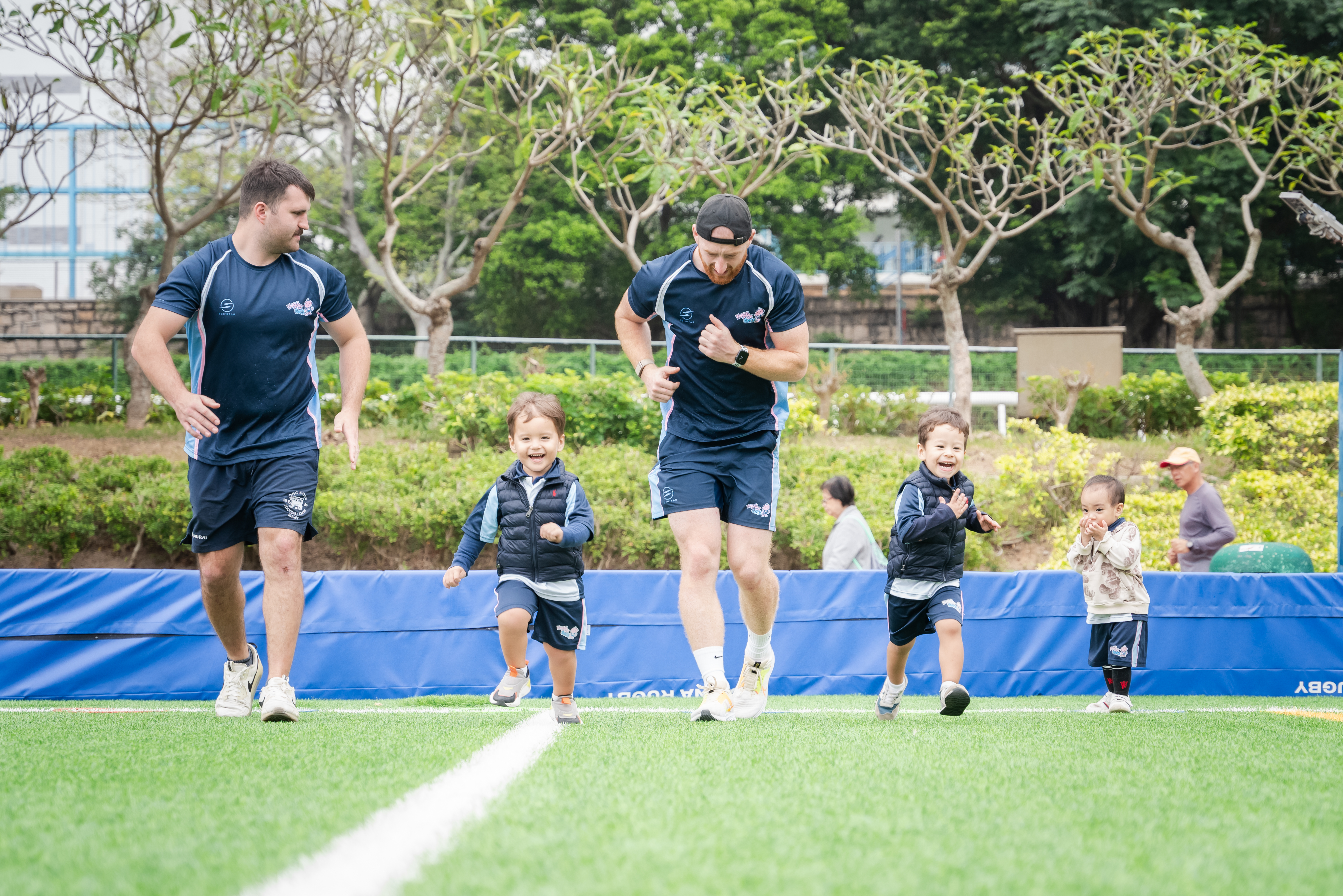 Group of smiling children holding party balloons and rugby balls for kids rugby party